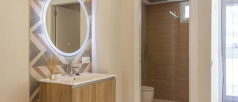 A modern bathroom with a vanity, mirror, and shower.