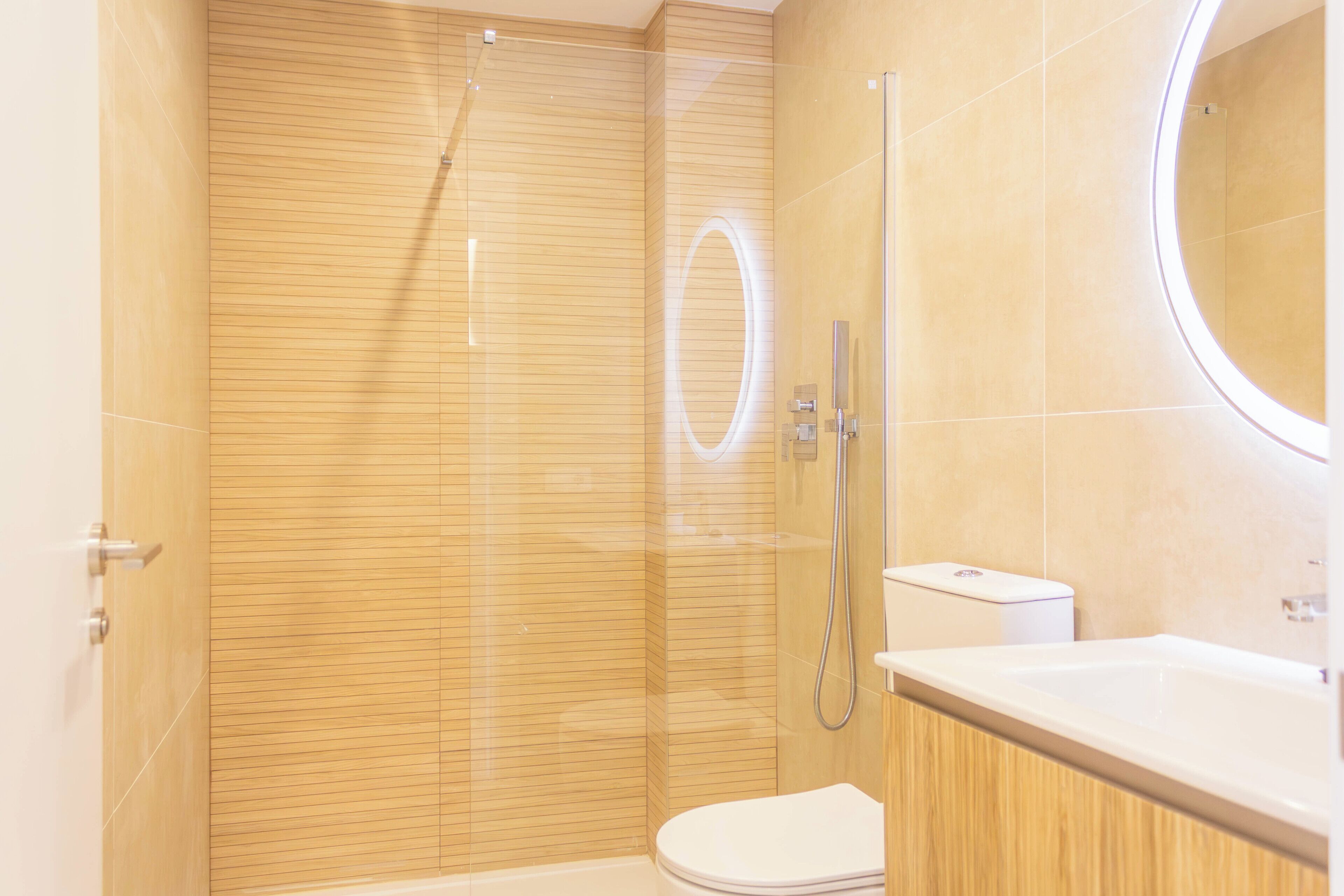 A modern bathroom with a glass-enclosed shower, a toilet, and a sink with a mirror.