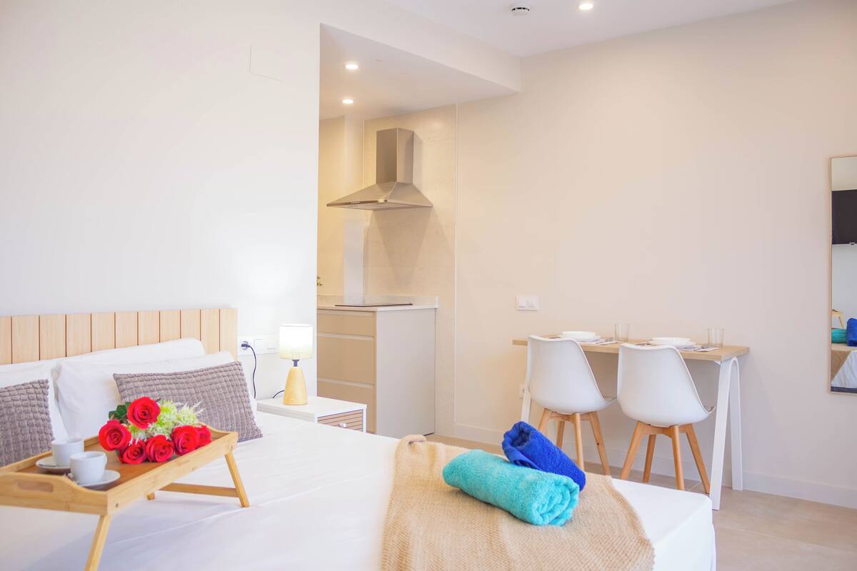 Habitación de hotel con cama, escritorio y kitchenette.