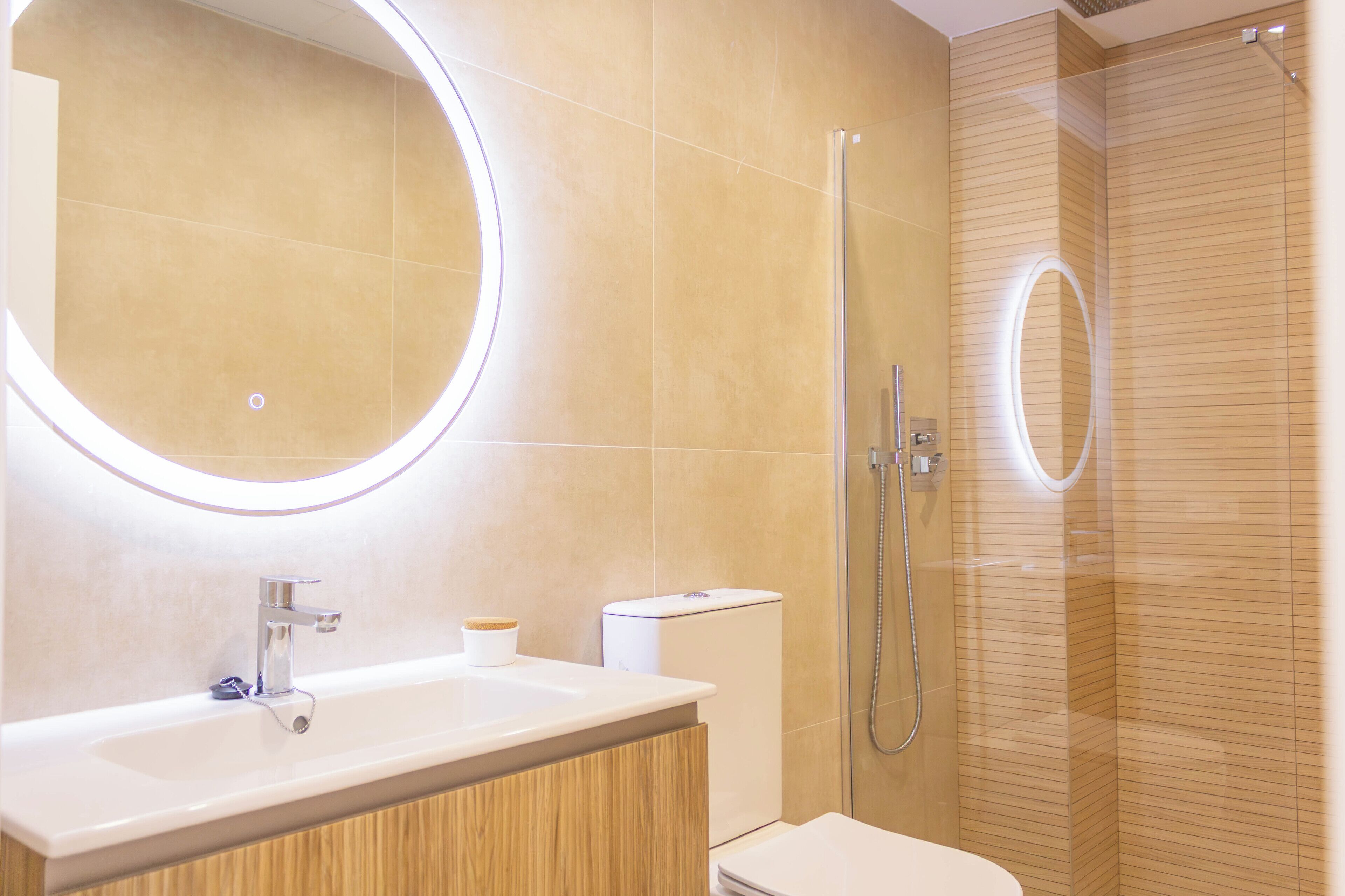 Een moderne badkamer met een wastafel, spiegel, toilet en douche.