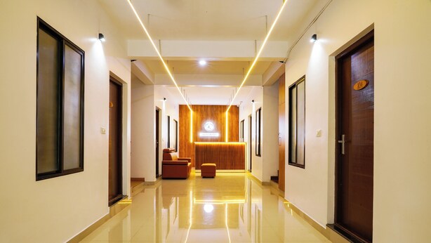 A hotel hallway with a reception desk, a wooden reception area, and a polished floor. - Charming 2-bedroom AC apartment Close to Rajagiri Hospital (KL)