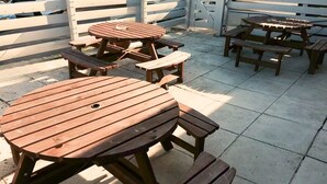 A patio area with wooden picnic tables and benches. - The Beacon Hotel, Cardiff, Part of the AG Collection (Cardiff)