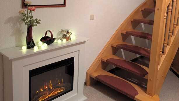 A fireplace with a modern design, a wooden staircase, and a framed artwork above it.