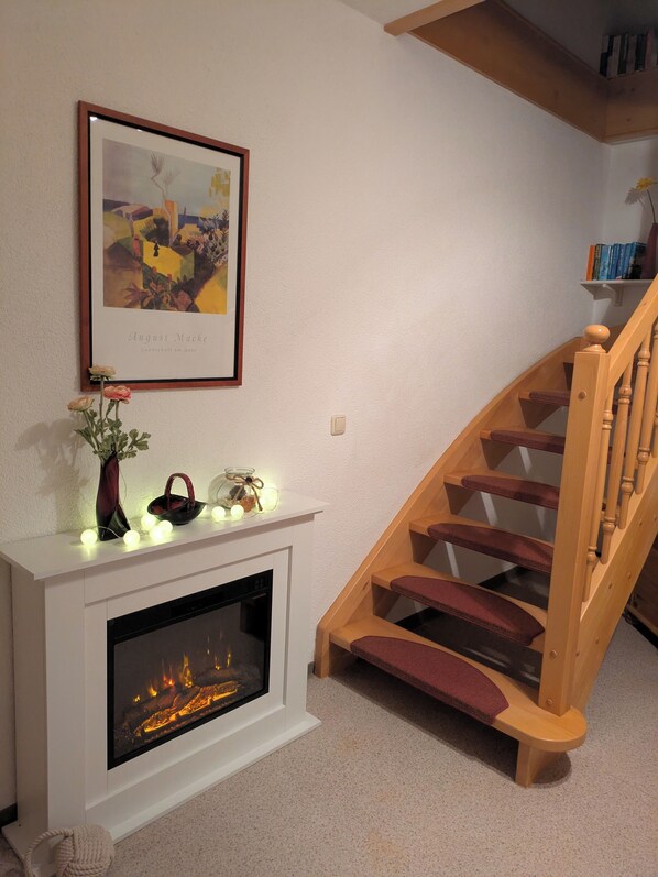 A fireplace with a modern design, a wooden staircase, and a framed artwork above it. - 250 m from the Woblitzsee - quiet apartment with WLAN, terrace, bicycle garage (Wesenberg)