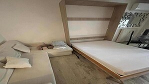 A compact room with a bed, a sofa, and a small table.