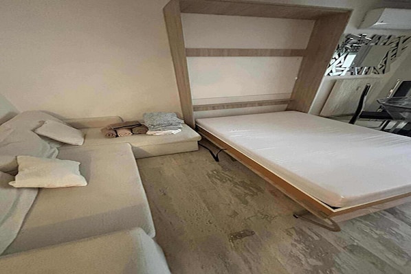 A compact room with a bed, a sofa, and a small table.
