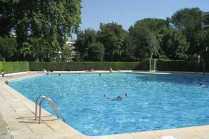 A swimming pool surrounded by greenery and a clear sky. - Superb studio apartment for 4 people (Mandelieu-la-Napoule)