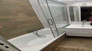 A modern bathroom with a glass-enclosed shower, a white sink, and a mirror above the sink.