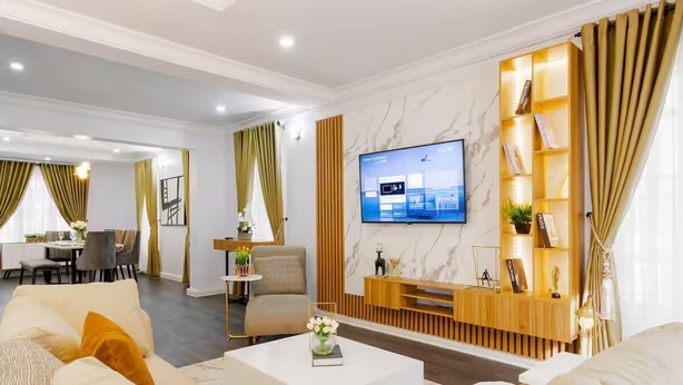 A modern living room with a flat-screen TV, a sofa, a coffee table, and a wooden entertainment unit.