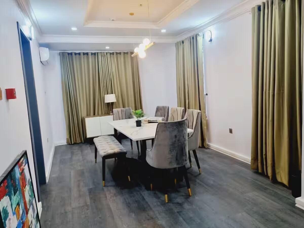 A dining area with a rectangular table, six chairs, and a chandelier.