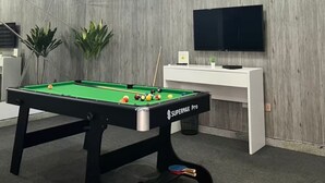 A modern room with a pool table, a flat-screen TV, and a wooden accent wall.
