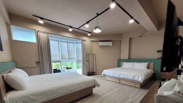 A hotel room with two beds, a TV, and a window with curtains.