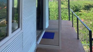 A modern building with a balcony, large windows, and a view of a green landscape. - Boho-Luxe Pool Villa with Simply Amazing Views by Setting Sun Boutique Homes (ตำบล เกาะลันตาใหญ่)