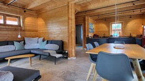 Een knus blokhutinterieur met een bank, eettafel en keukenhoek.