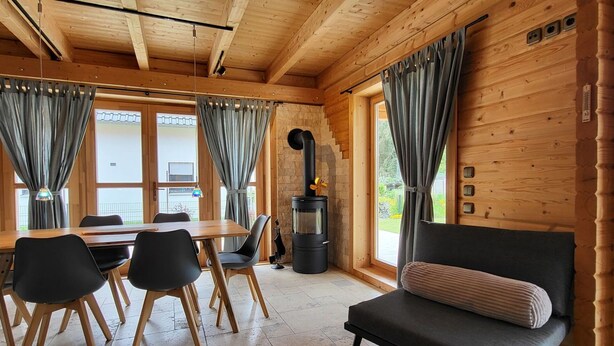 Een knus interieur van een blokhut met een eethoek, een bank en een houtkachel.