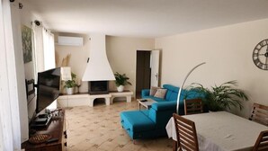 A living room with a sofa, a TV, a fireplace, and a dining area with a table and chairs. - Peace of mind (Saint-Cézaire-sur-Siagne)