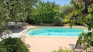 A swimming pool with a white lounge chair and a table, surrounded by greenery. - Peace of mind (Saint-Cézaire-sur-Siagne)