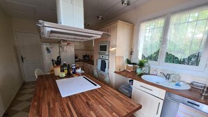 A compact kitchen with a wooden countertop, a built-in oven, a sink, and a window with a view of greenery. - Peace of mind (Saint-Cézaire-sur-Siagne)