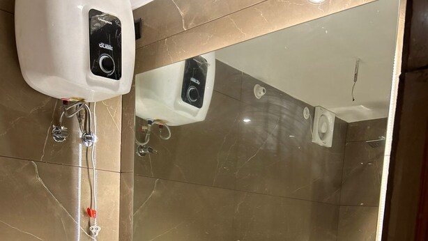 Um banheiro moderno com pia branca, um espelho grande e um dispensador de álcool em gel.