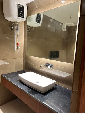 Ein modernes Badezimmer mit einem weißen Waschbecken, einem großen Spiegel und einem Handdesinfektionsmittelspender.