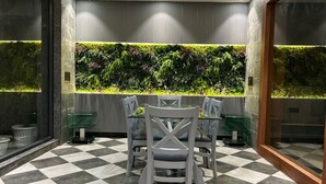 A dining area with a checkered floor, a table with chairs, and a wall with a vertical garden. - Ganga Euphoria Villa (Rishikesh)
