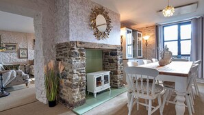 Un intérieur rustique avec une cheminée en pierre, des meubles blancs et une grande fenêtre.