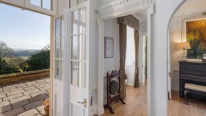 Una habitación con un amplio ventanal que da a un balcón con suelo de piedra y vistas al campo.