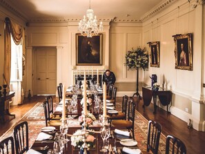 A formal dining room with a long table set for a meal, surrounded by chairs, a chandelier, and framed portraits on the walls. - Wonderful  villa for 19 people with pool, WIFI, TV, terrace and pets allowed (Saltash)