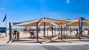 An outdoor fitness area with exercise equipment and shaded structures. - Hayarkon Royal in Tel Aviv-yafo (Tel Aviv)