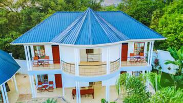 A two-story building with a blue roof, multiple balconies, and a covered outdoor area.
