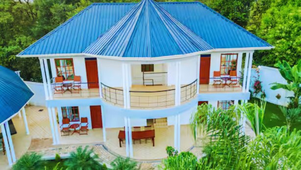 A two-story building with a blue roof, multiple balconies, and a covered outdoor area.