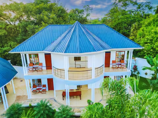 A two-story building with a blue roof, multiple balconies, and a covered outdoor area.