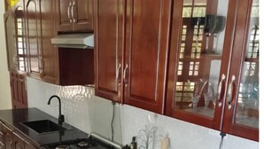 A kitchen with wooden cabinets, a black countertop, a stove, and a sink.