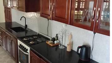 A kitchen with wooden cabinets, a black countertop, a stove, and a sink.