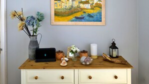Een houten dressoir met een laptop, een vaas met bloemen, een kaars en een lantaarn.