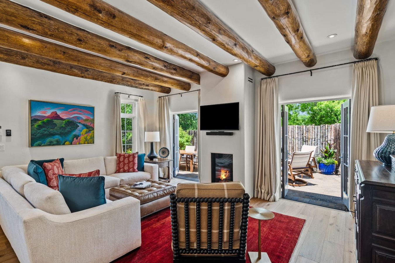 A living room with a sofa, armchair, fireplace, and a painting on the wall.