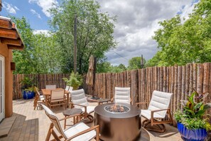 An outdoor patio with a fire pit, wooden chairs, and a table.