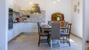 A modern kitchen with white cabinets, a wooden dining table, and hanging pendant lights. - Beautiful apartment for 7 people with A/C, WIFI and pets allowed (Donoratico)