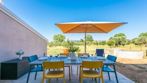 An outdoor patio with a table set for dining, surrounded by chairs and an umbrella. - Beautiful apartment for 7 people with A/C, WIFI and pets allowed (Donoratico)