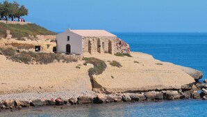 A coastal building with a white facade and a flat roof, situated on a sandy beach with a clear view of the sea. - Nice apartment for 3 guests with WIFI, A/C, TV and terrace (Porto Torres)