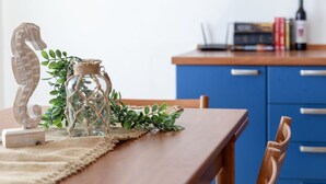 A wooden dining table with a glass bottle and a decorative seahorse. - Nice apartment for 3 guests with WIFI, A/C, TV and terrace (Porto Torres)