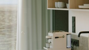A modern kitchen with a built-in coffee machine, a sink, and a view of the sea through a large window. - Glass-roof lodge with private spa & sauna near Seljalandsfoss, pure tranquility (Hvolsvöllur)