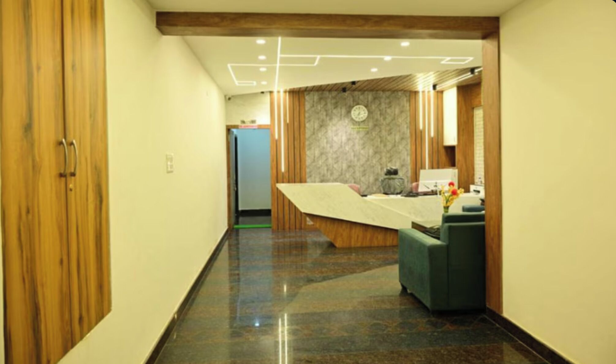 Un hall d’hôtel moderne avec un buffet en bois, un comptoir d’accueil et un mur en marbre.