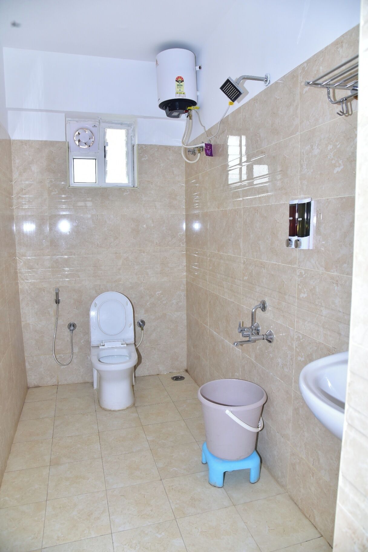 A bathroom with a toilet, bidet, and a bucket.