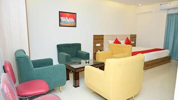 A hotel room with a bed, a sofa, a chair, and a small table.