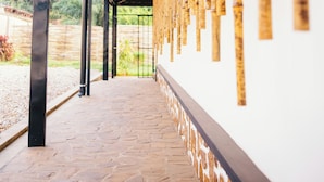 A covered walkway with stone flooring and a wall decorated with vertical bamboo elements. - Migano Residence (Bujumbura)