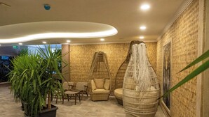 Un espacio de relax con mobiliario de mimbre, una planta en maceta grande y una pared con textura.