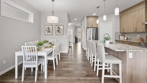 A modern kitchen with white cabinetry, a marble countertop, and pendant lighting.