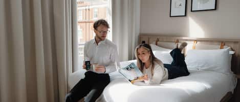 Una habitación de hotel con cama, cortinas e imágenes enmarcadas en la pared.