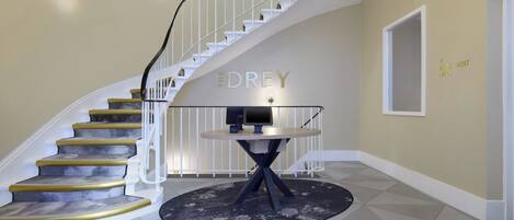 A staircase with a curved design, a round table with a monitor, and a wall with a nameplate.